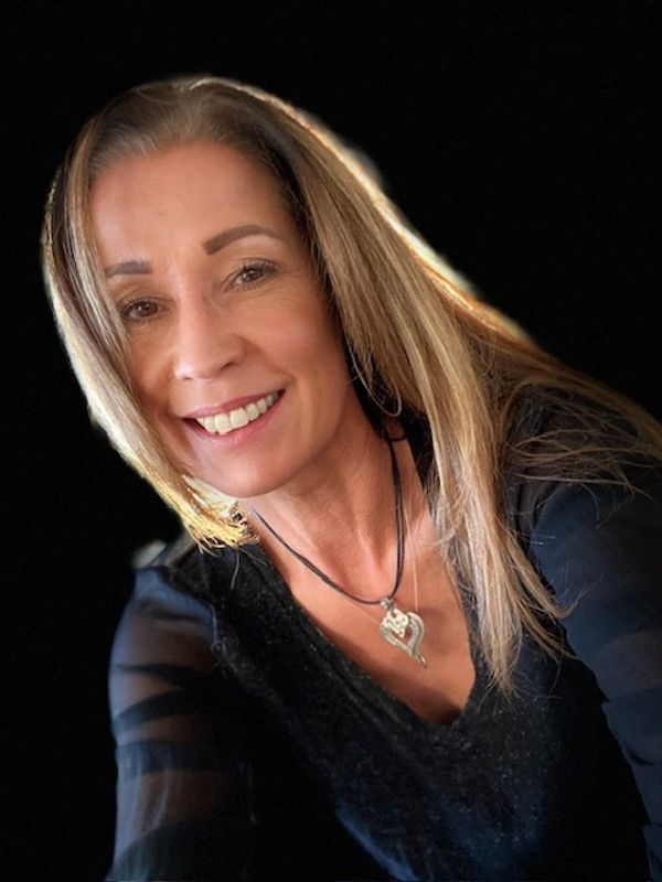 Smiling woman with long blonde hair against a black background.